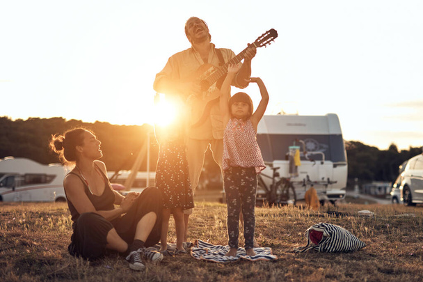 Οικογένεια σε διακοπές, τραγουδώντας, παίζοντας μουσική σε μια κιθάρα και απολαμβάνοντας καλοκαιρινές δονήσεις. - Φωτογραφία, εικόνα