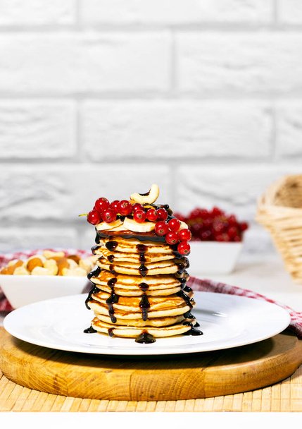 Panqueques con plátano, nueces y grosella roja sobre fondo blanco, Desayuno tradicional americano, Copyspace, Resolución vertical - Foto, Imagen