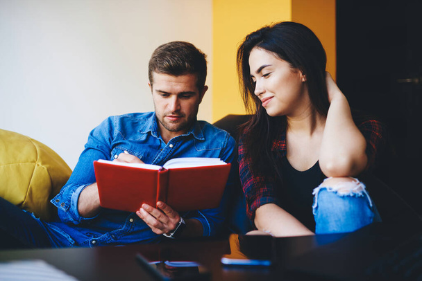 Young caucasian male and female student friends planning coursework project making notes, woman and man writing ideas for startup project cooperating and talking while sitting together indoors - Фото, зображення