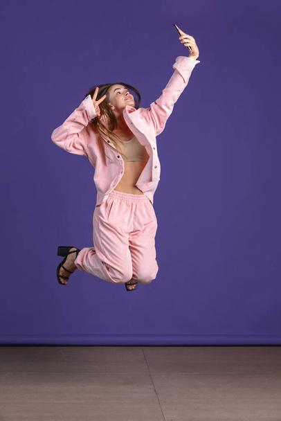 Ganztägiges Porträt eines jungen attraktiven Mädchens, das über lila Studiohintergrund springt - Foto, Bild
