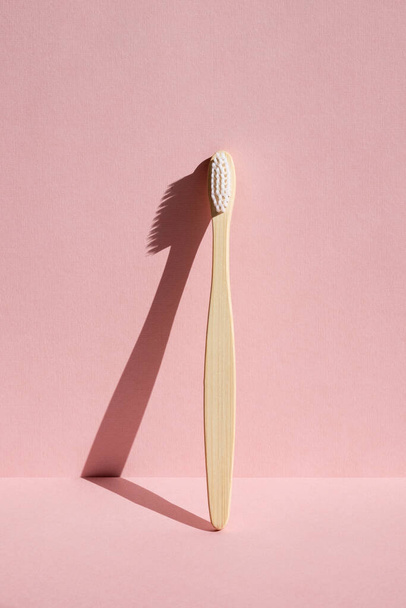 One eco friendly bamboo wooden toothbrush on a pink background. Hard light.  - Foto, Imagem