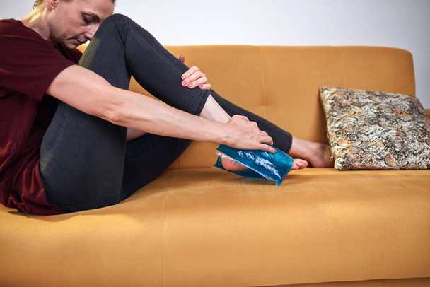 Γυναίκα με τραύμα στο πόδι από πόνο στο σπίτι χρησιμοποιώντας παγοκύστη. - Φωτογραφία, εικόνα