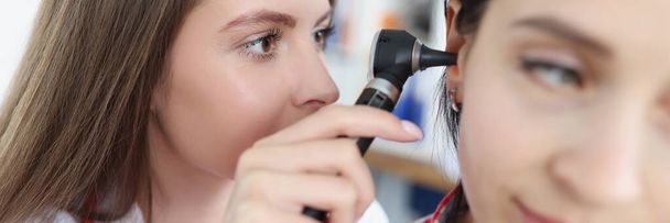 Γιατρός θεραπευτής εξετάζει αυτί της γυναίκας ασθενή με οστεοσκόπιο στην κλινική - Φωτογραφία, εικόνα
