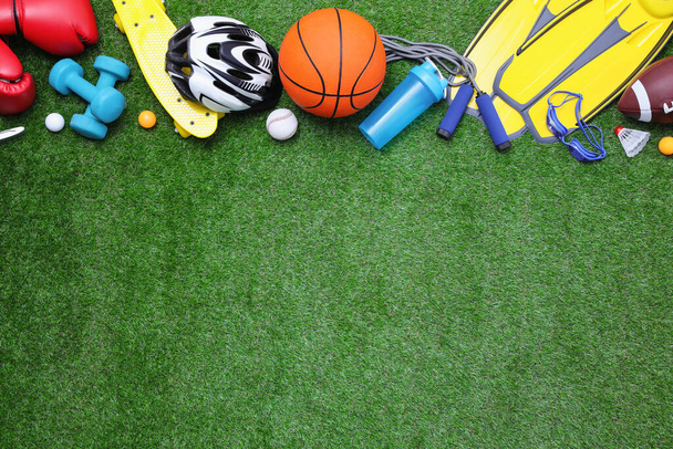Different sport equipment on green grass, flat lay. Space for text - Φωτογραφία, εικόνα