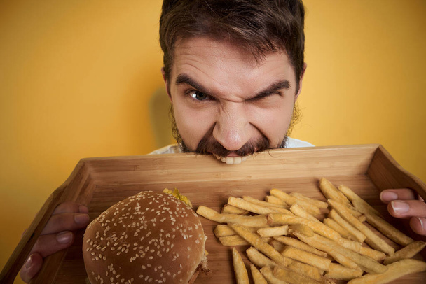 uomo barbuto vassoio di legno con fast food birra divertimento patatine hamburger - Foto, immagini