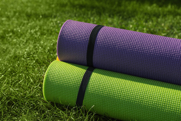 Bright exercise mats on fresh green grass outdoors, closeup - Фото, зображення