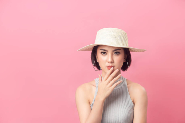 Femme asiatique cheveux courts portant chapeau en studio fond rose. - Photo, image