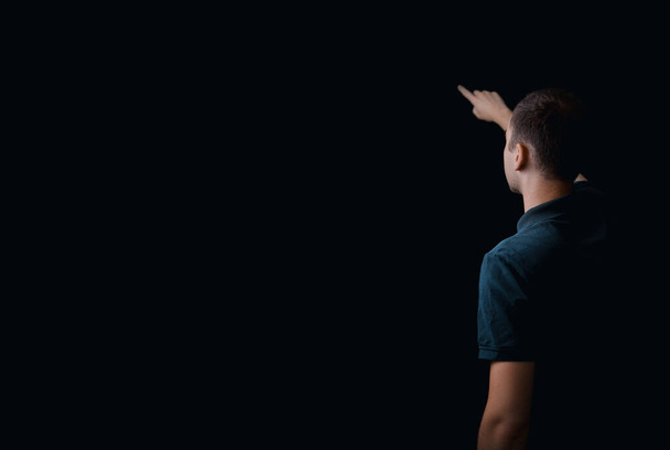 Dark background with a man. Free space for text or logo, copy space. Person on the black background, showing something with a hand. Only back visible. Modern template. - Photo, Image