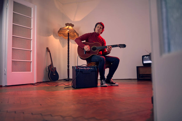 Male musician playing acoustic guitar on the amplifier in retro vintage room. - Photo, Image