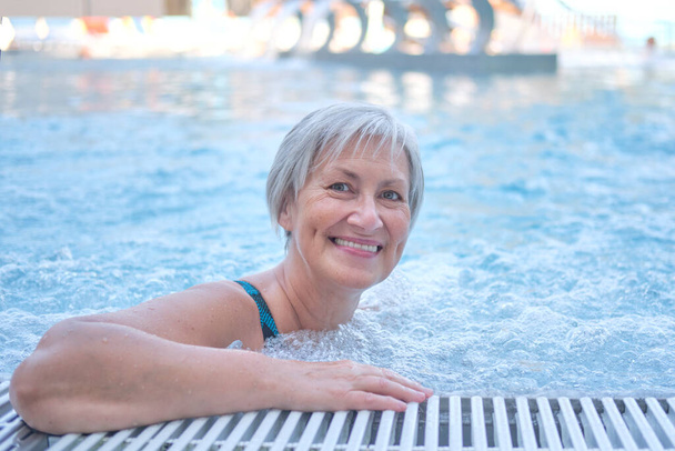 Mulher idosa com cabelos grisalhos na piscina termal exterior com hidromassagem. - Foto, Imagem