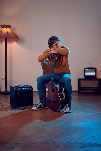 Músico masculino tocando guitarra acústica no amplificador na sala vintage retro. - Foto, Imagem