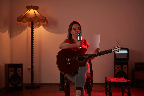 Nő zenél és énekel egy vezeték nélküli mikrofonon egy retro vintage szobában. - Fotó, kép