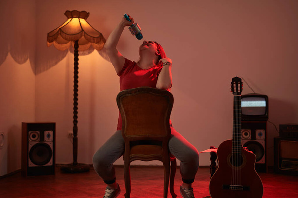Woman playing music and singing on a wireless microphone in a retro vintage room. - Photo, Image