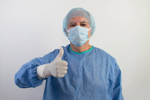 A fő téma nem fókusz, öreg férfi sebész állni fehér háttér egységes orvos egészségügyi sürgősségi szakma segít az embereknek hüvelykujj fel kéz szimbólum orvosi kesztyű sebészeti hajháló - Fotó, kép