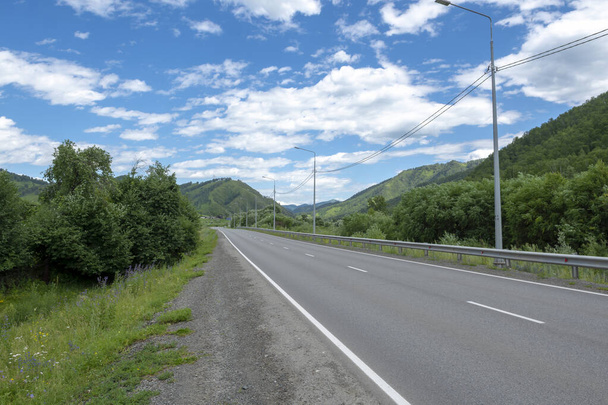 carretera carretera y picos de montaña en el fondo de un cielo azul con nubes - Foto, imagen