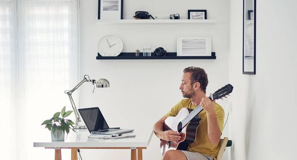 Man playing acoustic guitar at home. - Фото, зображення