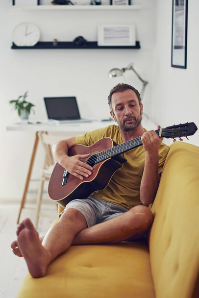Человек, играющий на акустической гитаре дома
. - Фото, изображение