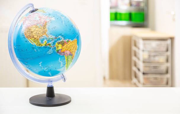 Globe kouluplaneetta Maa opiskelijapöydällä, hämärän huoneen sisätausta. Koulutus, kartografia, maat ja maailman poliittinen kartta, takaisin kouluun käsite - Valokuva, kuva