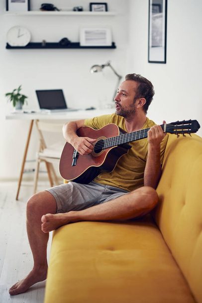 Άνθρωπος που παίζει ακουστική κιθάρα στο σπίτι. - Φωτογραφία, εικόνα