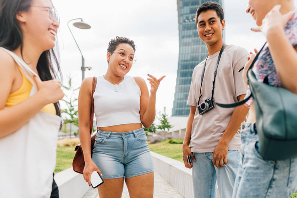 Grupo de jóvenes amigos multiétnicos al aire libre charlando y contando chismes divirtiéndose juntos vinculación - Foto, Imagen