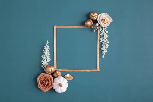 Still life of gold and white elements with a frame for text on a turquoise background. Minimalistic autumn concept - Fotografie, Obrázek
