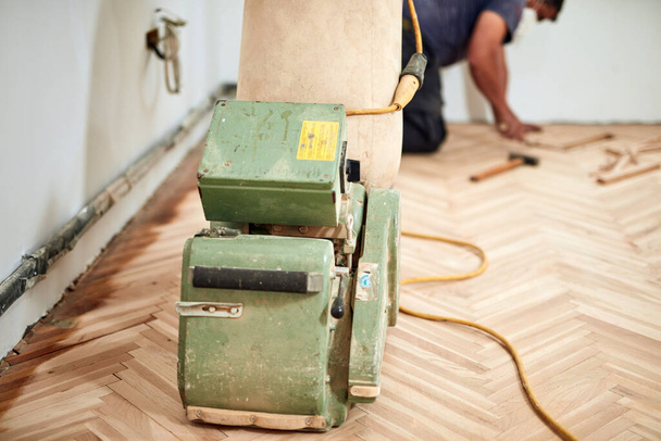 Repairman restoring parquet with a sanding machine. - Photo, Image