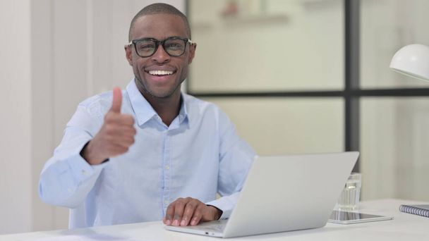 Polegares para cima por homem africano com laptop no trabalho  - Foto, Imagem