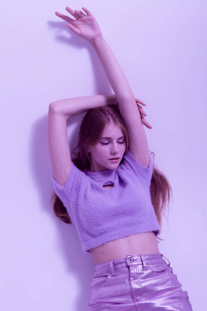 beautiful girl in fashionable, summer clothes, purple illumination lies on the floor - Фото, зображення