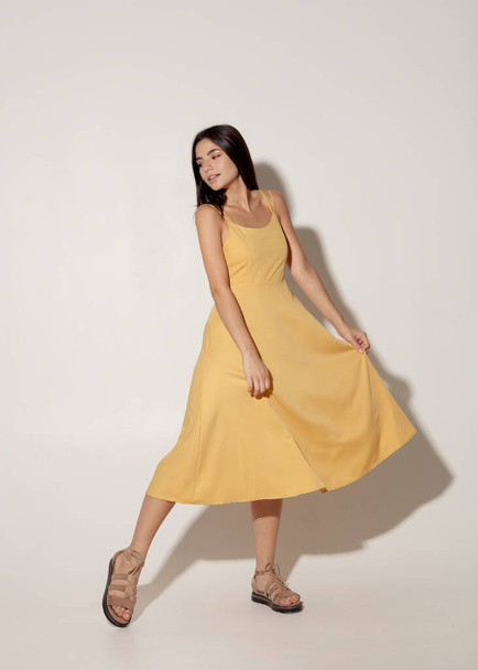 beautiful brunette in a yellow evening dress dancing - Fotografie, Obrázek