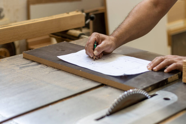 carpintero carpintero está cortando madera con la máquina de corte de madera eléctrica industrial para la fabricación de muebles en el taller - Foto, Imagen