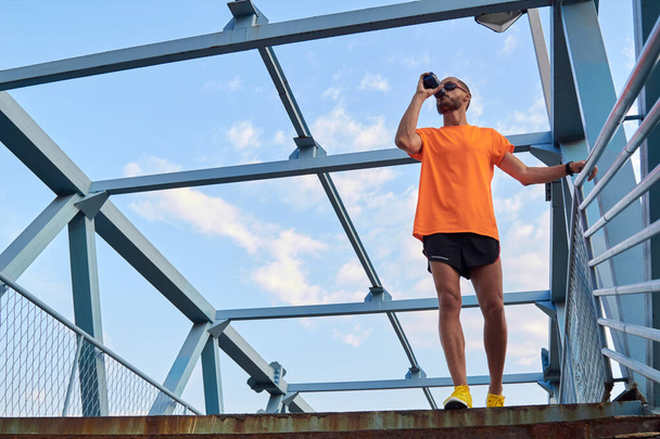 Sportsman boire de l'eau après le jogging et l'exercice en zone urbaine. - Photo, image
