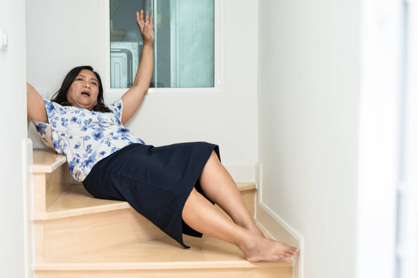 アジアの中年女性の患者は滑りやすい表面のために階段を下ります - 写真・画像