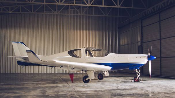 Small white private jet parked in the hangar - Zdjęcie, obraz