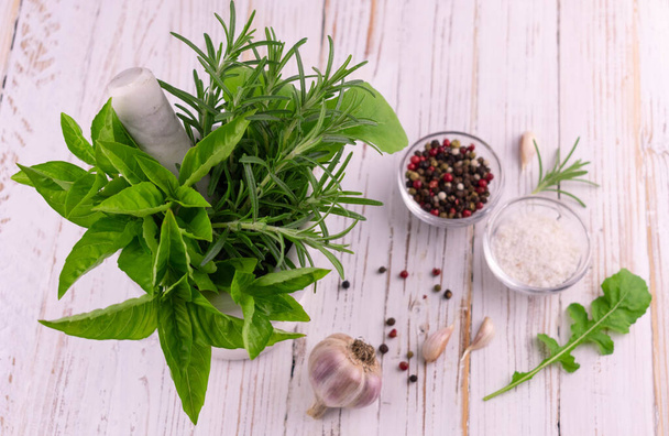 Fresh green garden herbs in mortar and spices on a white wooden table.  - Photo, Image