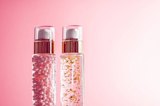 Luxe huidverzorgingsproducten in glazen flessen op roze achtergrond - Foto, afbeelding