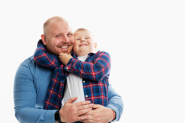Dad and son, 6-7 years old, hug and laugh. Happy family relationships, love and tenderness. White background. Space for text. - Photo, image
