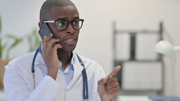 Médico africano hablando por teléfono en la clínica - Foto, imagen