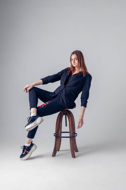 a red-haired girl is sitting on a chair leaning back - 写真・画像