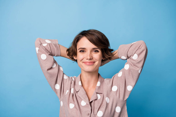 Top nad vysokým úhlem pohledu fotografie veselé okouzlující žena relaxovat oblečení pyžama držet ruce hlava izolované na modrém pozadí - Fotografie, Obrázek