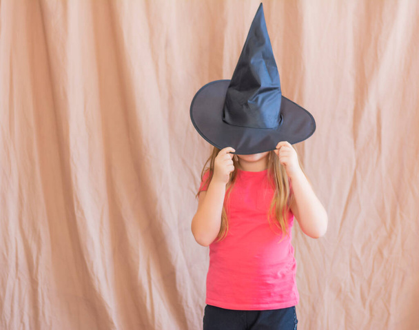 Fairy sorceresses girls 6-7 years old covering their eyes with a black witch hat - 写真・画像