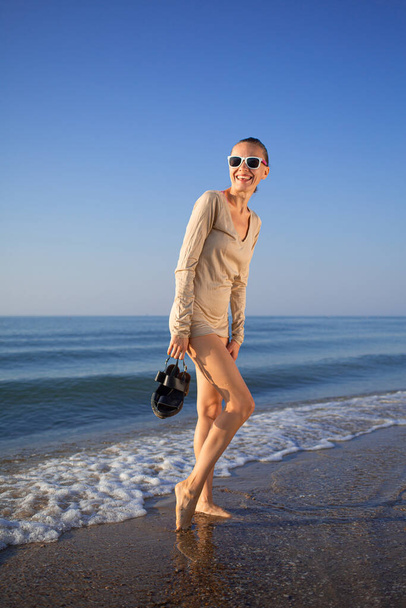 Krásná žena kráčí po pláži s modrým mořem a oblohou - Fotografie, Obrázek