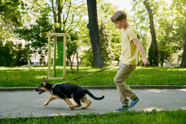 Cheerful boy running with puppy at summer park - Foto, Imagem