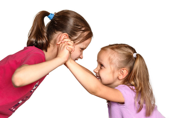 Kampf zwischen zwei kleinen Mädchen. Kinder albern auf weißem Hintergrund herum - Foto, Bild