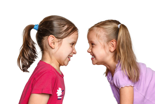 Aggression und Streit zwischen zwei kleinen Mädchen. Kinder streiten sich auf weißem Hintergrund - Foto, Bild