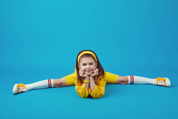 Niño en traje amarillo haciendo divisiones, ejercicio de estiramiento, pose de ángulo recto - Foto, imagen