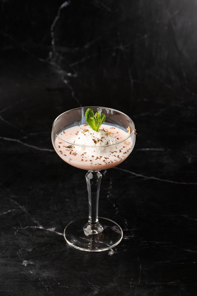 Glass of ice cold Baileys cocktail served in a glass, decorated with mint leaf placed on a black background - Fotografie, Obrázek