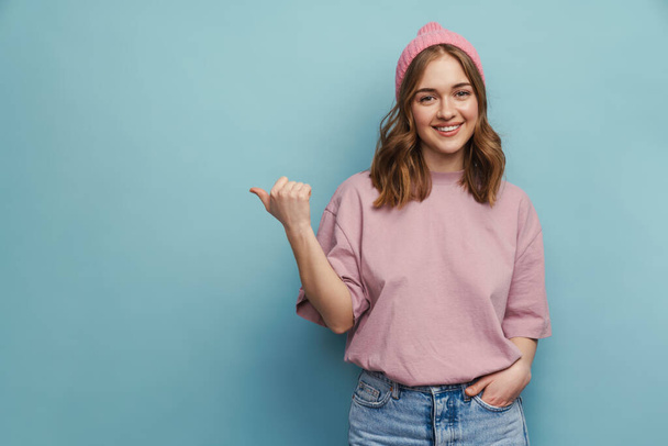 Young happy woman smiling and pointing finger aside isolated over blue background - Foto, afbeelding