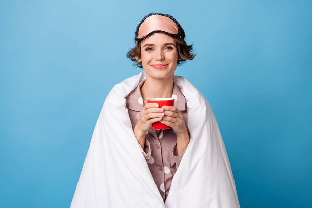 Photo of young happy positive smiling cheerful girl covered in blanket drinking tea isolated on blue color background - 写真・画像