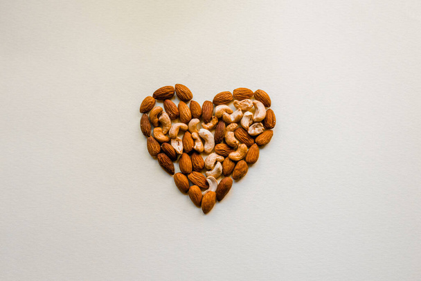 Nuts are laid out on a white background in the shape of a heart. - Foto, Imagem
