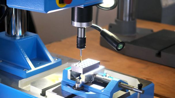 Máquina de corte de metal na exposição de tecnologia de hardware. HDR. Close-up de uma máquina moderna fazendo buracos em forma redonda em uma folha de metal. - Foto, Imagem